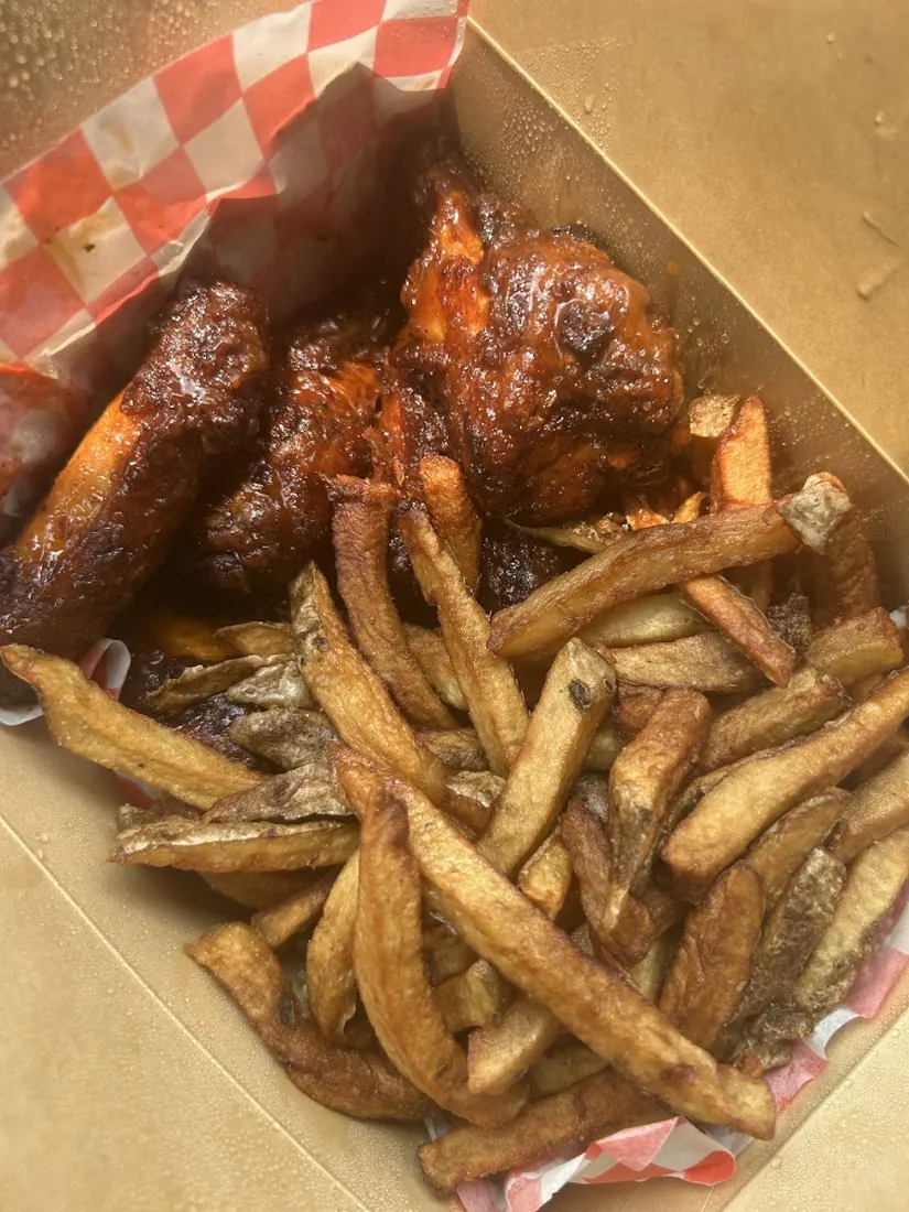 Jerk wings and fries in a cardboard takeout box